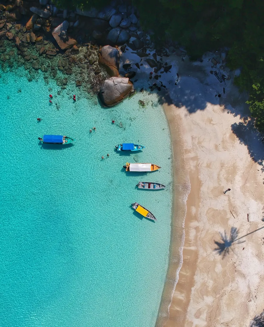 Praia turquesa com pequenos barcos — destinos da Sagis Tour
